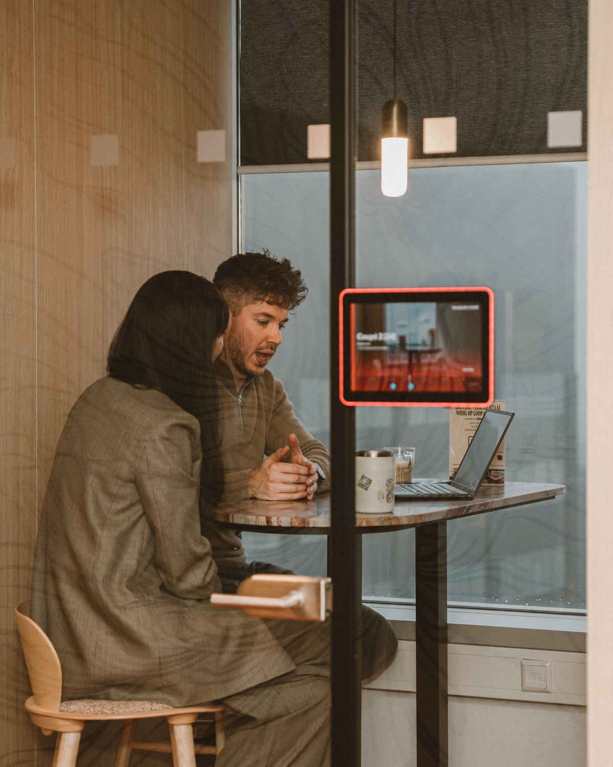 Twee collega's van PSHQ in gesprek aan een hoge tafel met een laptop